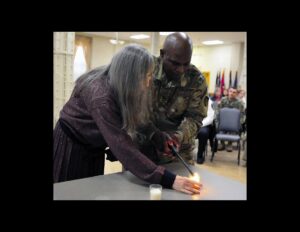 Marguerite Mishkin, Holocaust child survivor, and Sgt. 1st Class, Babatunde Akala, Equal Opportunity adviser, U.S. Army Sustainment Command, light the first candle in a lighting ceremony as part of the observance held at Rock Island Arsenal, Illinois.